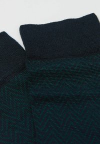 Calcetines de color verde oscuro y azul marino con un diseño de zigzag texturizado y puños acanalados, fabricados con un material de punto suave.