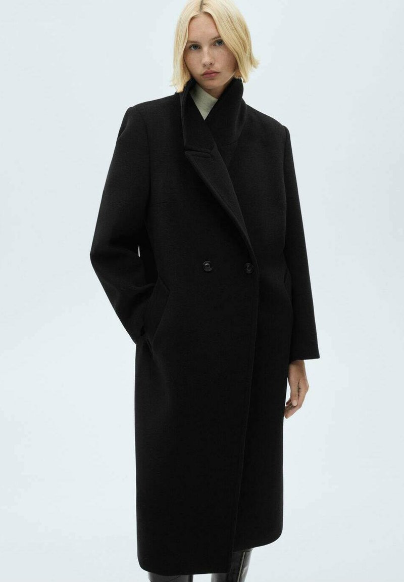 Cappotto in lana nera con design doppiopetto, ampi revers e tasche laterali. Presenta una linea dritta e una texture liscia.
