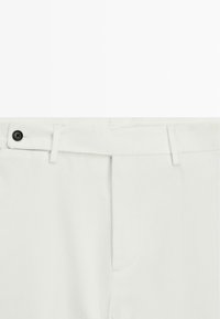 Białe bawełniane spodnie o prostym kroju, z czarnym zapięciem na guzik oraz kieszeniami po bokach, o gładkiej teksturze i minimalistycznym designie.