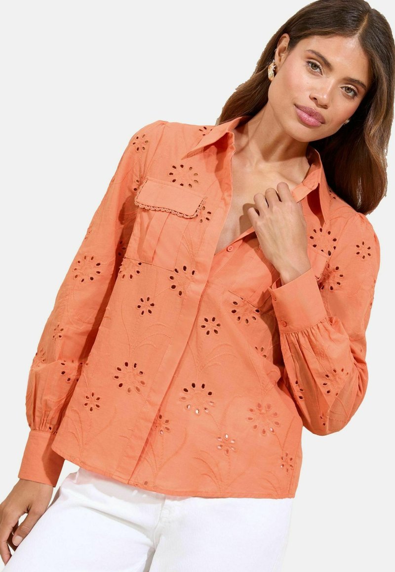 Oranges Baumwollhemd mit floralem Stickerei, Knopfleiste und Brusttasche. Verfügt über lange Ärmel mit gerafften Manschetten und einem lockeren Schnitt.