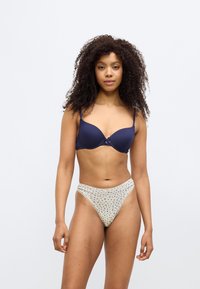 Μπλε καπιτονέ σουτιέν με ρυθμιζόμενες τιράντες και λεπτομέρεια φιόγκου στο μπροστινό μέρος, σετ με μπεζ σλιπ ψηλόμεσο με λουλουδάτο μοτίβο.