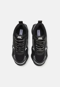 Sneaker nere in materiale mesh e sintetico, con accenti bianchi, punta arrotondata e lacci standard. Logo visibile sulla linguetta.