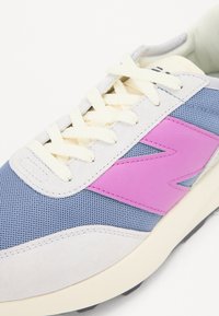 Läbimurde sneakers, mis on kujundatud heledates hallides, sinistes ja roosades toonides, valmistatud nahast ja võrgumaterjalist, tekstureeritud detailidega ning kreemjattest paeltega.