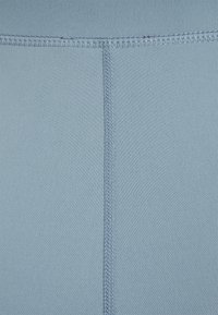 Tecido azul claro com uma textura suave, apresentando costuras planas e um design simples. A superfície é homogénea, sem padrões ou acentos visíveis.