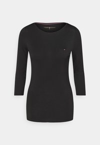 Maglia nera a maniche lunghe con scollatura rotonda e discreto logo Tommy Hilfiger nell'angolo in alto a sinistra. Design semplice ed elegante.