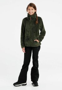 Fleecejacke in dunkelgrün mit hohem Kragen, Reißverschluss und zwei Seitentaschen, kombiniert mit schwarzen Hosen und schwarzen Schuhen.
