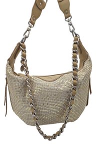 Sac à main beige tissé avec une lanière en cuir lisse. Comprend un accent en chaîne et un léger éclat, avec une forme arrondie et des pampilles sur les côtés.