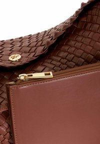 Brown woven leather handbag with a flap closure, gold hardware, and a front zippered pocket in smooth leather. Textured surface and clean lines.