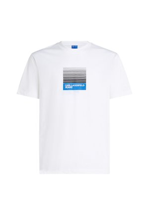 T-shirt bianca in cotone a maniche corte con stampa grafica di linee nere e blu e testo "KARL LAGERFELD JEANS" centrato sotto.