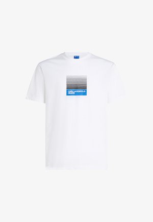 T-shirt bianca in cotone a maniche corte con stampa grafica di linee nere e blu e testo "KARL LAGERFELD JEANS" centrato sotto.