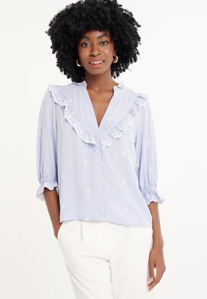 Lichtblauwe blouse met een gerimpelde kraag en mouwen, voorzien van witte geborduurde patronen. Relaxte pasvorm met driekwartmouwen en een v-hals.