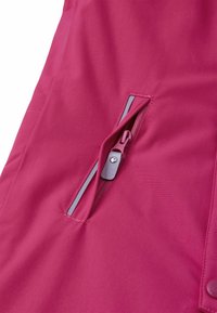 Il tessuto fucsia presenta una tasca con zip di colore grigio chiaro, dettagli cuciti lungo i bordi e una consistenza liscia in tutto il materiale.