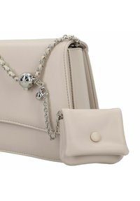 Beige Lederhandtasche mit silberner Kettenriemen, strukturierte Form und einer Fronttasche mit Knopfverschluss. Glatte Textur, minimalistisches Design.