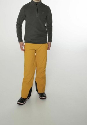 Pull en polaire gris avec demi-fermeture éclair et manches longues, associé à un pantalon imperméable jaune avec des accents noirs, et des bottes imperméables noires.