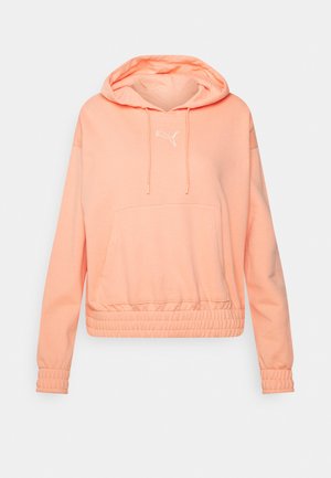 Długa bluzka z kapturem w kolorze brzoskwiniowym, z przednią kieszenią kangurką, regulowanym ściągaczem kaptura, ściągaczami na mankietach oraz białym logo Puma na piersi.