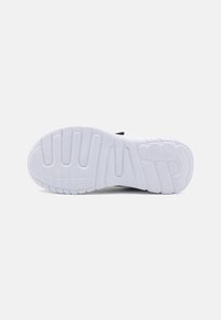 Semelle de chaussure en caoutchouc blanc avec des rainures et des crêtes texturées pour une meilleure adhérence. Design minimaliste avec un profil plat et des bords arrondis.