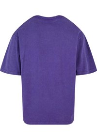 T-shirt en coton violet avec un col rond, des manches courtes et une coupe décontractée. Le tissu a une texture lisse et uniforme avec des coutures doubles.