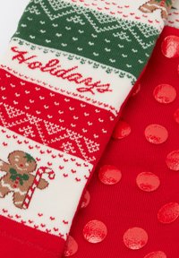 Rood-witte sokken met feestelijk thema, met een peperkoekontwerp, groene accenten en glanzende rode polkadots op het onderste gedeelte.