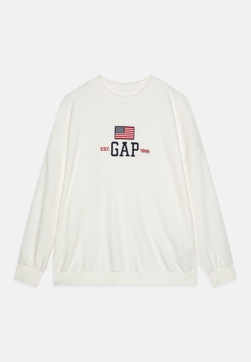 Sudadera blanca de manga larga con un logo "GAP" en navy y una bandera americana bordada encima, cuello redondo y puños elásticos.