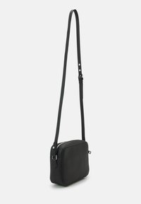 Čierna crossbody taška vyrobená z textúrovanej kože, obdĺžnikový tvar, úzky ramenný popruh s nastaviteľnou dĺžkou, strieborný zips.