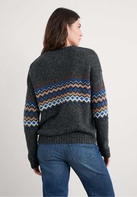 Siv volneni pulover z vzorcem fair isle v rjavi, modri in kremni barvi. Hrbtni del je sproščenega kroja z rebrastim robom in dolgimi rokavi.