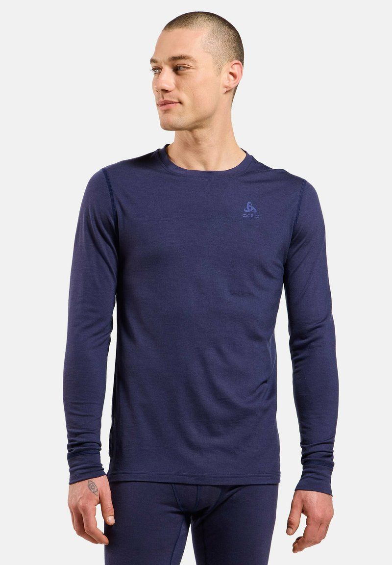 T-shirt de performance à manches longues navy, en tissu léger, col rond, design ajusté, avec un logo discret sur le haut de la poitrine.