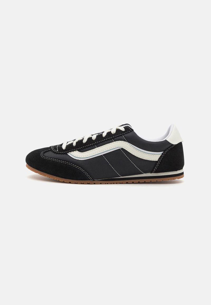 Svart mocka och nylon sneakers med en vit sidostripa, vita snören och en gummisula, i en lågprofil design.