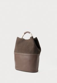 Sac à main en suède et cuir marron avec une forme structurée. Il dispose d'une poignée ronde et d'un contraste de couture le long de la couture.