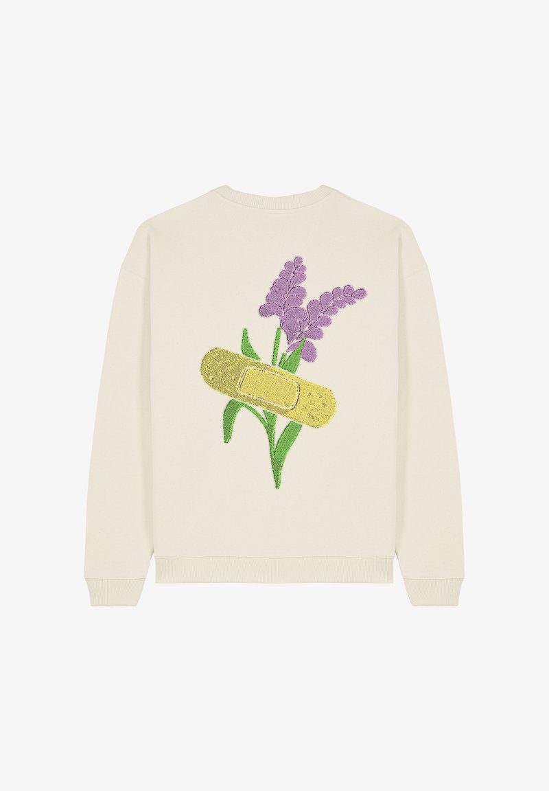 Sweatshirt crème comportant un design graphique de fleurs violettes et un bandage jaune, agrémenté de détails texturés.