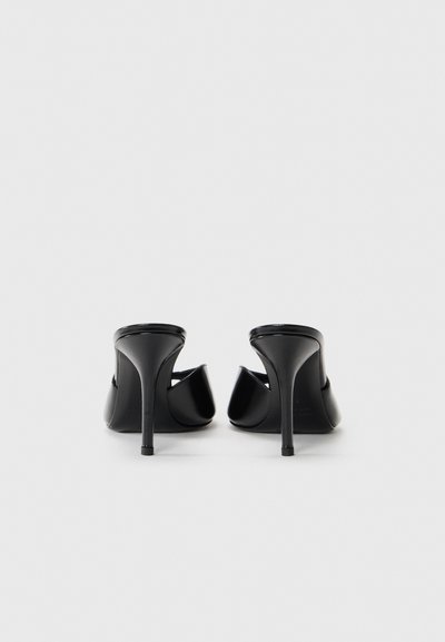 Chaussures à talons hauts noires avec un design à dos ouvert, texture lisse et talons stilettos fins. Style minimaliste sans logos visibles.