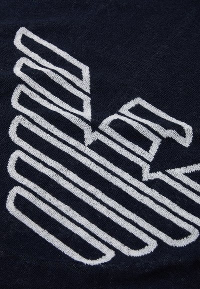 Navy towel featuring a prominent white embroidered geometric design with textured lines and shapes, creating a contrasting visual effect.