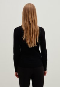 Mustat pitkähihainen neule pehmeästä kankaasta, vartalonmyötäinen malli, pyöreä pääntie, sileä pinta ja minimaalinen yksityiskohta takana.