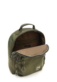 Maslinasto zeleni najlon ruksak s patentnim zatvaračem na vrhu, malom ručkom i bež unutrašnjošću koja sadrži džep i oznaku brenda.