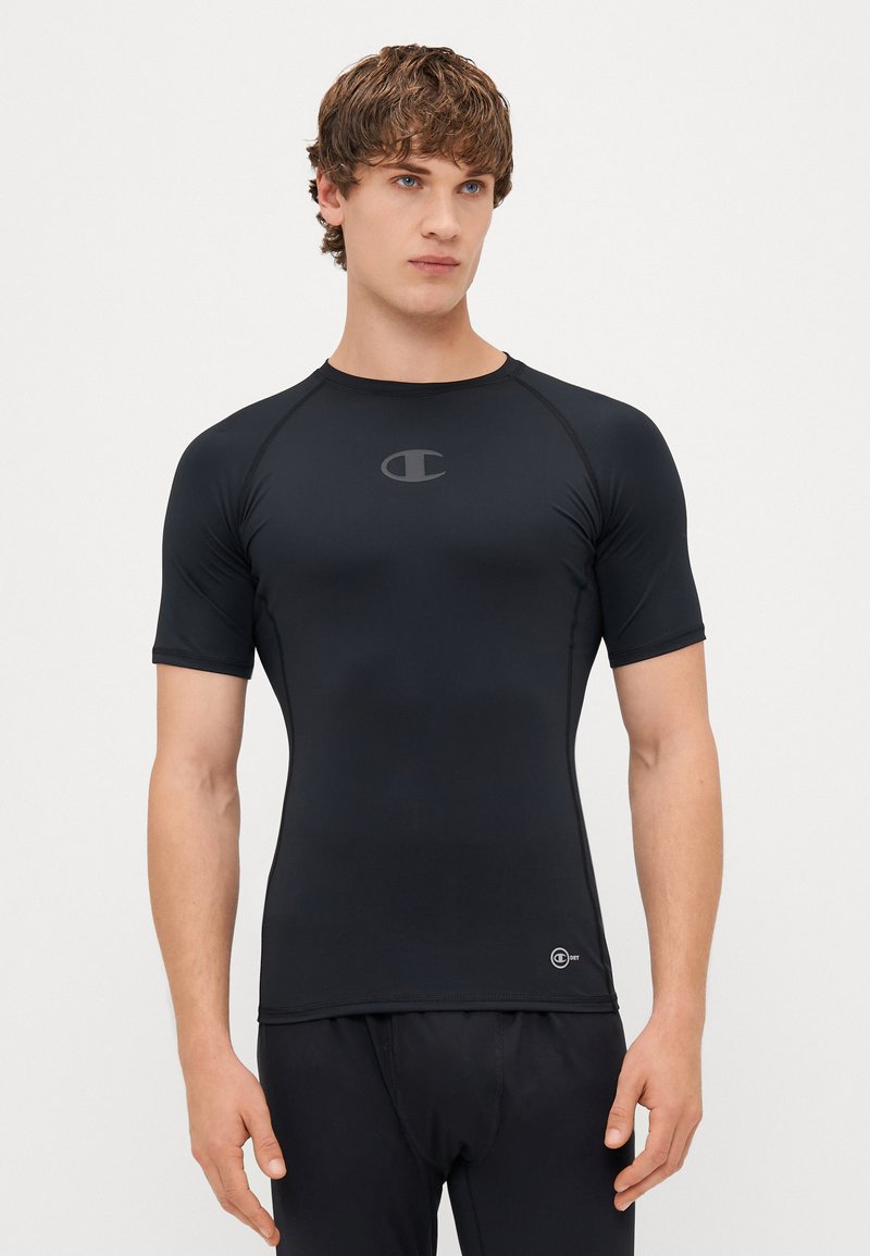 T-shirt de sport noir à manches courtes en matériau extensible. Il possède un col rond et un logo sur la poitrine. Texture lisse.