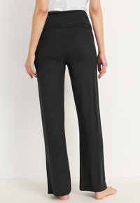 Zwarte, wijde broek met een hoge tailleband. Gemaakt van zachte stof, met een gladde textuur en zonder zichtbare patronen of accenten.
