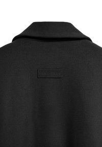 Abrigo negro con un collar doblado, tejido texturizado, que presenta una etiqueta rectangular en relieve "POLO CLUB" en la parte posterior.