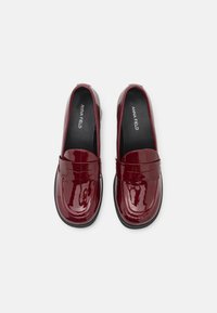 Burgundské lakované kožené mokasíny s zaoblenou špičkou, šitými detaily a hladkým povrchem. Černé vkládací stélky s logem "ANNA FIELD".