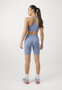 Lichtblauw sportset bestaande uit een aansluitende beha met kruisbanden op de rug en high-waisted shorts, beide met een gestructureerd patroon.