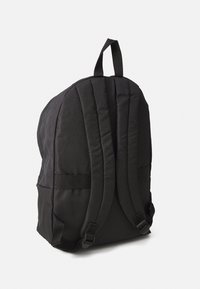 Schwarzer Stoff-Rucksack mit einer geschwungenen Form, gepolstertem Rücken und Schultergurten sowie verstellbaren Clips. Verfügt über einen oberen Tragegriff.