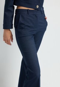 Námořnické modré kalhoty na míru z texturované tkaniny, s rovnými nohavicemi, předními kapsami a elegantním pasem s poutky na pásek.