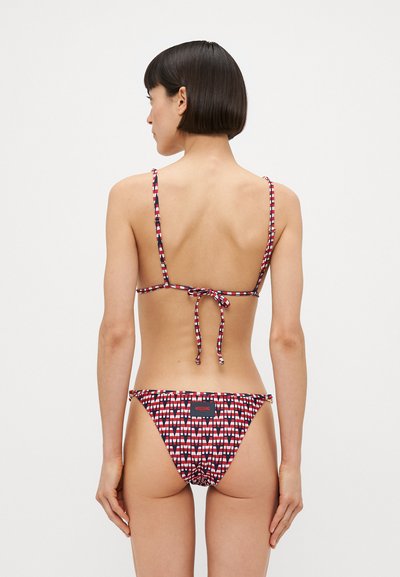 Biquíni com padrão vermelho e branco, com alças finas, laços nas costas ajustáveis e parte de baixo de corte baixo. Apresenta uma etiqueta da marca na cintura.