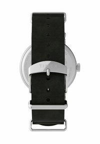 Montre Timex avec un boîtier rond en acier inoxydable, bracelet en cuir noir, boucle en argent et plusieurs trous pour l'ajustement de la taille.