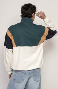 Felpa a girocollo color block con pannelli in teal scuro, blu navy, senape e bianco; colletto alto e tessuto morbido.
