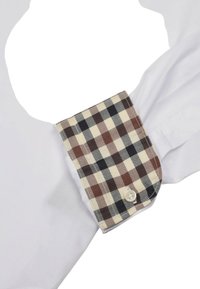 Weißes Hemd mit Kragen, das an den Manschetten ein karierte Muster in Braun und Creme aufweist und über einen Knopfverschluss verfügt. Glatte Stofftextur.