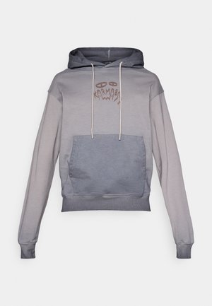 Szürke és kék színkockás kapucnis pulóver kenguru zsebbel, kapucnival és húzózsinórokkal. A mellrészen grafikai mintával rendelkezik. Puha tapintású.