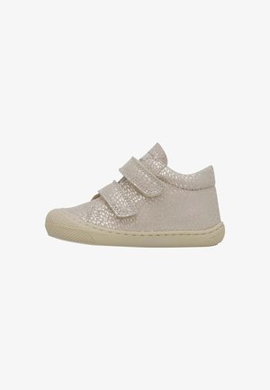 Zapatos de niño pequeño en color beige con una superficie texturizada y brillante, que cuentan con dos tiras de Velcro y una suela de goma con punta redondeada.