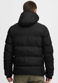 Black puffer jacket with a hood, featuring a quilted design and prominent horizontal seams. The texture is smooth with a glossy finish.