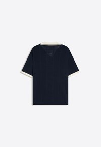Chemise en maille bleu marine manches courtes avec col et bords de manches blancs, présentant un motif vertical texturé.