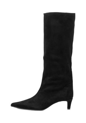 Bota de ante negra hasta la rodilla con punta afilada y tacón bajo en forma de kitten, de pie sobre un fondo blanco.