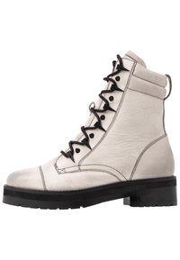 Buty z off-white skórki z czarnymi sznurówkami. Posiadają okrągły czubek, wyściełany kołnierz oraz masywną czarną podeszwę. Widoczne przeszycia.